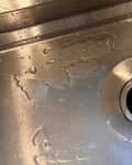 Someone spraying stainless steel kitchen sink.