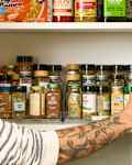 head on shot of an assortment of spices and other pantry items in a kitchen cabinet.