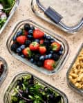 counter with glass containers full of food prep: berries, pasta, salad, beans