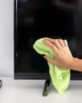A person drying off their freshly-cleaned television screen with a dry microfiber cloth