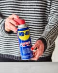 A woman holding a can of WD-40 multi-use product