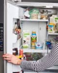 A woman opens the door of her refrigerator