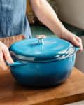 Hands holding handle of $50 Dutch oven.