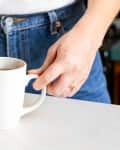 Someone dipping tea bag into tea mug.