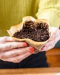 Someone holding a coffee filter with spent gounds.