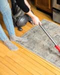 Someone vacuuming a kitchen rug.