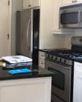 Kitchen with white island, cabinetry. and black countertops.