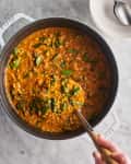 Ladling some lentil soup out of a dutch oven
