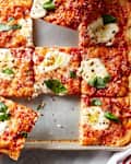 Hands taking slices of focaccia pizza.