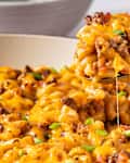 someone scooping out casserole from pot