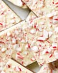 Overhead shot of pieces of peppermint bark, topped with crumbled candy cane.