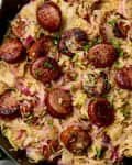 Overhead shot of cooked sauerkraut and sausage in a cast iron pan.