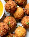 overhead shot of a plate of fried goat cheese balls, with a side of mustard dipping sauce.