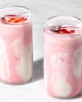 angled shot of two glasses full of a strawberry cloud smoothie
