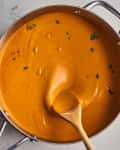 sauce in pan with basil leaves and wooden spoon