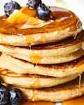 Stacks of pancakes, drizzled with syrup and garnished with blueberries, on a plate