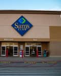 Sam's Club entrance with welcome and exit signs, shopping carts, and a pharmacy sign on the left.