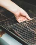 Hand lifting a grill grate from the grill