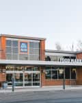 Brick exterior of an Aldi food market with shopping carts outside and large windows.