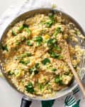 Broccoli and cheese risotto in a pan with a wooden ladle