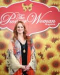 Woman in floral shawl standing in front of sunflower backdrop with "The Pioneer Woman Magazine" sign.
