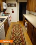 Narrow kitchen with wooden cabinets, patterned runner rug, white appliances, and a small mirror on the wall.