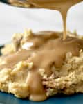 Creamy mashed potatoes topped with rich brown gravy on a teal plate.
