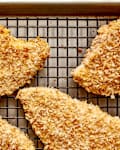 Crispy breaded chicken cutlets on a wire rack, showcasing a golden-brown coating.