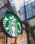 Starbucks logo on a circular sign outside a modern glass building.