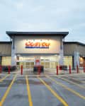 Costco Wholesale storefront with shopping carts and red bollards in the parking lot.