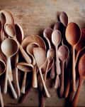 Assorted wooden spoons of various sizes and shades on a wooden surface.