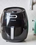 Cozyna air fryer on a kitchen counter with wooden utensils and a green toaster.