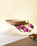 Ceramic bowl on beige fabric with three purple tulips.