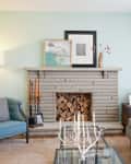 Living room with a gray brick fireplace, blue armchair, gray sofa, and decorative art on the mantel.