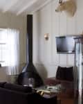 Living room with black fireplace, mounted goat head, wall-mounted TV, glass coffee table, and dark sofa.
