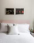 Bed with white and polka dot pillows, pink headboard, and two framed photos above.