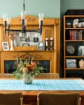 Dining room with wooden table, floral centerpiece, bookshelves, and decorative fireplace.
