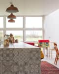 Kitchen with patterned tile island, copper pendant lights, vintage stove, and large windows overlooking greenery.