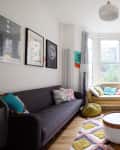Bright living room with gray sofa, yellow loveseat, colorful rug, round coffee table, and wall art.