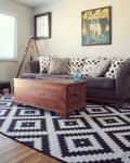 Living room with a gray sofa, polka dot pillows, wooden chest coffee table, and geometric black and white rug.