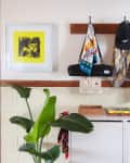 Entryway with coat rack holding jackets, hats, and scarves. A plant and books on a white cabinet, framed art on the wall.
