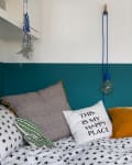 Cozy bedroom with star-patterned bedding, colorful pillows, abstract wall art, and a dreamcatcher.