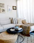 A round coffee table with a decorative wooden bead strand and a stack of magazines
