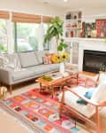 Bright living room with gray sofa, colorful rug, sunflowers on coffee table, and built-in shelves around a fireplace.