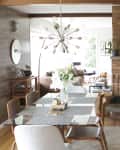 Mid-century modern dining room with glass table, white chairs, brick fireplace, and a sputnik chandelier.