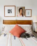 Cozy bedroom with wooden headboard, framed art, two lamps, and a cat sleeping on a bed with a patterned blanket.