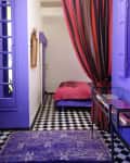 Purple painted walls with a red curtain separating the space between a bedroom and a living area