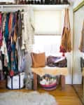 Colorful clothing rack, shoes on shelf, leather bags on a fur-covered bench, and woven baskets in a cozy closet space.