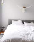 Bed with white bedding, gray headboard, and wall-mounted bull skull decor.