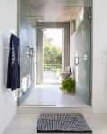 Modern bathroom with glass shower, concrete walls, striped towel, potted fern, and window view of greenery.